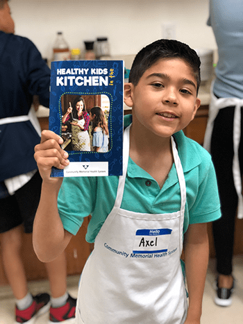 A kid holding up a cookbook